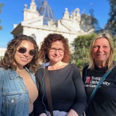 three women smiling in front of italian architecture