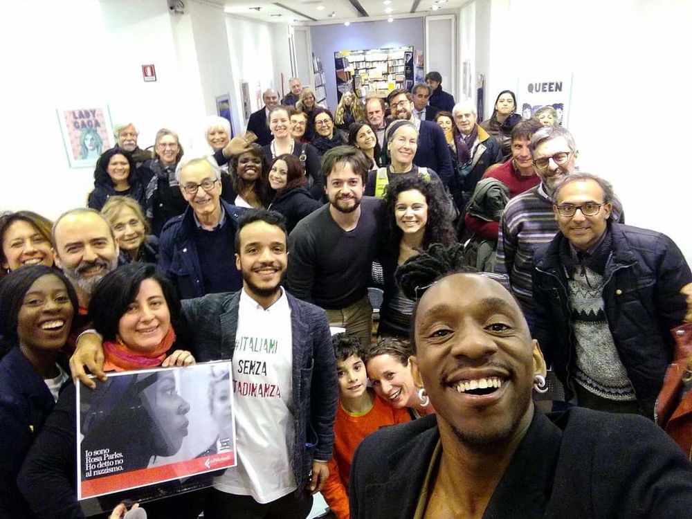 Group of people smiling with poster of "io sono rosa parks" 