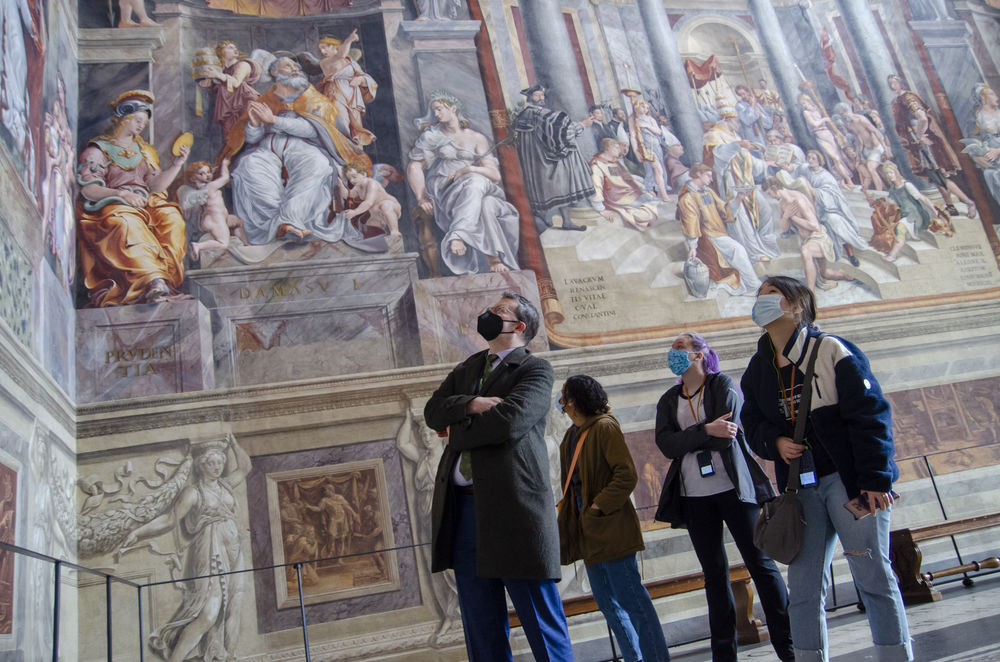 A group of students and their professor looks up at the frescos at the Vatican Museum