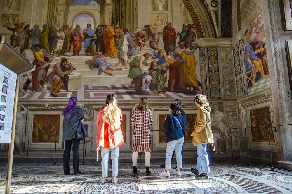 A group of students and their professor look up at the frescos at the Vatican Museum