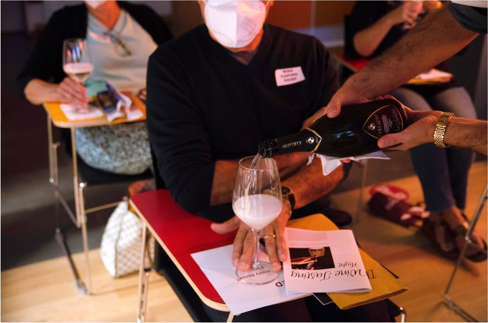 Person sitting at desk being poured wine