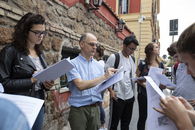 A group of students read worksheets outside in Rome