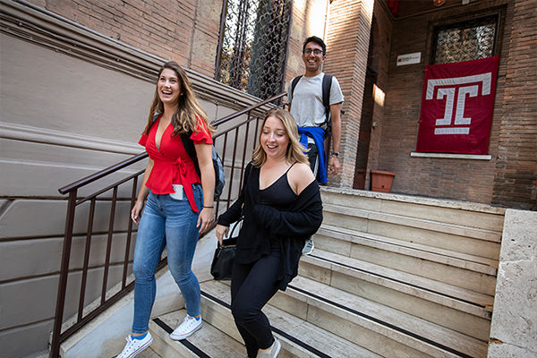 Two female and one male student walking down the steps at Temple Rome