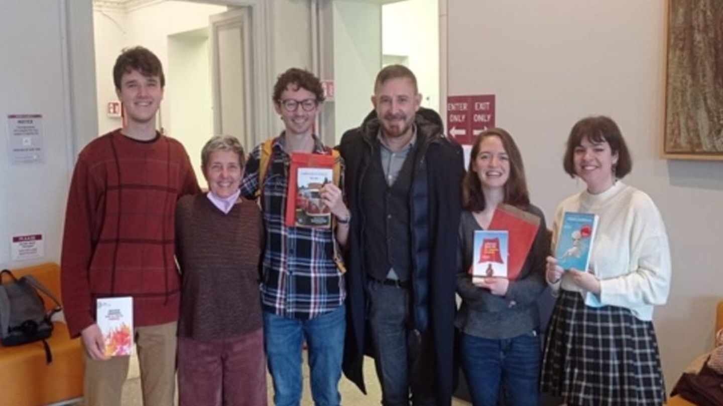 A group of six people (students and professors) smiling with books in hand
